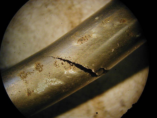 图4.通过低功率显微镜观察，锯齿状的，不规则的应力腐蚀破裂（SCC）在不锈钢油线的这一部分中很容易看到。